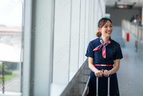 Portrait female Cabin crew or air hostess in airport. Cabin crew, air hostess working in airplane. Service mind. Asian stewardess with suitcase at modern airport terminal. flight attendant