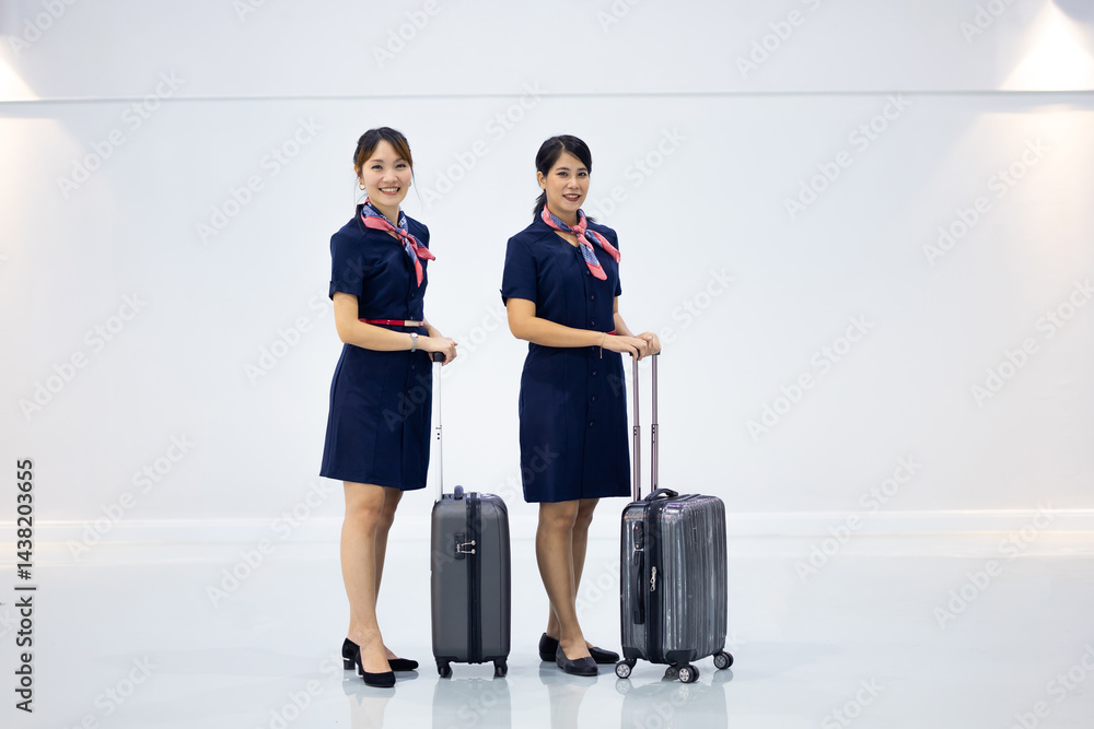 Portrait two Cabin crew or air hostess in airport. Cabin crew, air hostess working in airplane. Service mind. Asian stewardess with suitcase at modern airport terminal. flight attendant