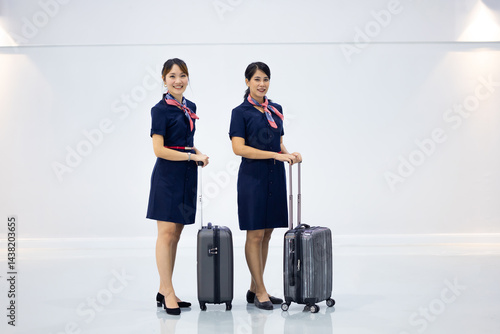 Obraz na płótnie Portrait two Cabin crew or air hostess in airport. Cabin crew, air hostess working in airplane. Service mind. Asian stewardess with suitcase at modern airport terminal. flight attendant w salonie