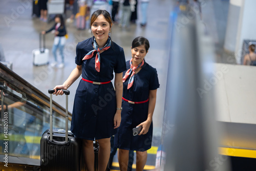 Back view two Cabin crew or air hostess in airport. Cabin crew, air hostess working in airplane. Service mind. Asian stewardess with suitcase at modern airport terminal. flight attendant