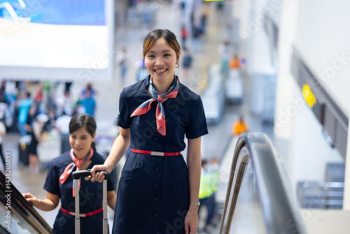 Back view two Cabin crew or air hostess in airport. Cabin crew, air hostess working in airplane. Service mind. Asian stewardess with suitcase at modern airport terminal. flight attendant