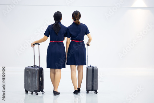 Obraz na płótnie Back view two Cabin crew or air hostess in airport. Cabin crew, air hostess working in airplane. Service mind. Asian stewardess with suitcase at modern airport terminal. flight attendant w salonie