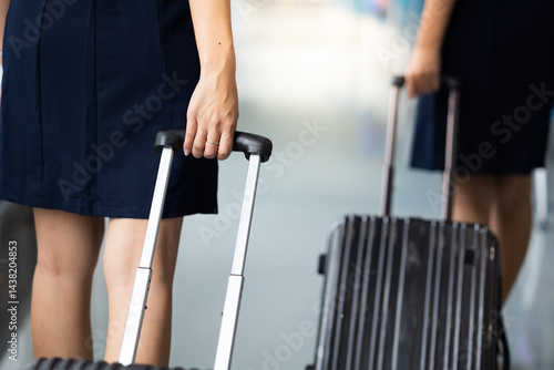 Obraz na płótnie Closeup hand woman Walking in airport. Cabin crew, air hostess working in airplane. Service mind. Asian stewardess with suitcase at modern airport terminal. flight attendant w salonie