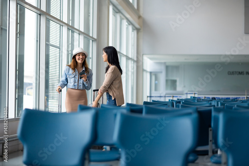 Obraz na płótnie Happy Asian Female Travelling use smartphone. Happy asian woman passenger traveler waiting for departure with suitcase at modern airport terminal w salonie
