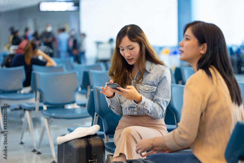 Internet Online Check flight schedule on smartphone. arrival and departure board. Two Asian woman use smartphone cheking flight for travel in long weekend