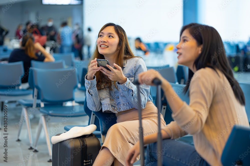 Internet Online Check flight schedule on smartphone. arrival and departure board. Two Asian woman use smartphone cheking flight for travel in long weekend