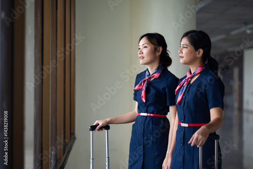 Obraz na płótnie Portrait two Cabin crew or air hostess in airport. Cabin crew, air hostess working in airplane. Service mind. Asian stewardess with suitcase at modern airport terminal. flight attendant w salonie