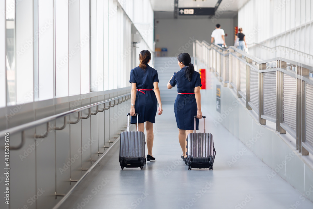 Rear view Two woman friends walking in airport. Cabin crew, air hostess working in airplane. Service mind. Asian stewardess with suitcase at modern airport terminal. flight attendant