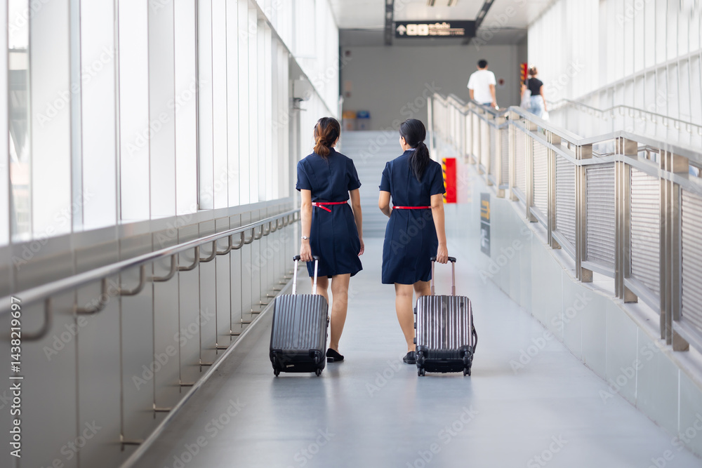Rear view Two woman friends walking in airport. Cabin crew, air hostess working in airplane. Service mind. Asian stewardess with suitcase at modern airport terminal. flight attendant
