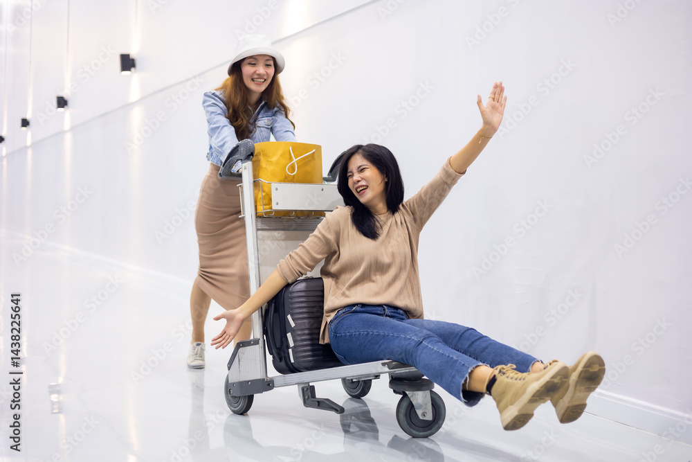 Riding baggage trolley. two Happy Asian beautiful woman passenger traveler and friends having fun with luggage at the airport