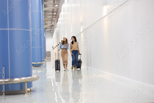 Obraz na płótnie Two Happy Asian Female Friends Travelling Together. Happy asian woman passenger traveler waiting for departure with suitcase at modern airport terminal w salonie
