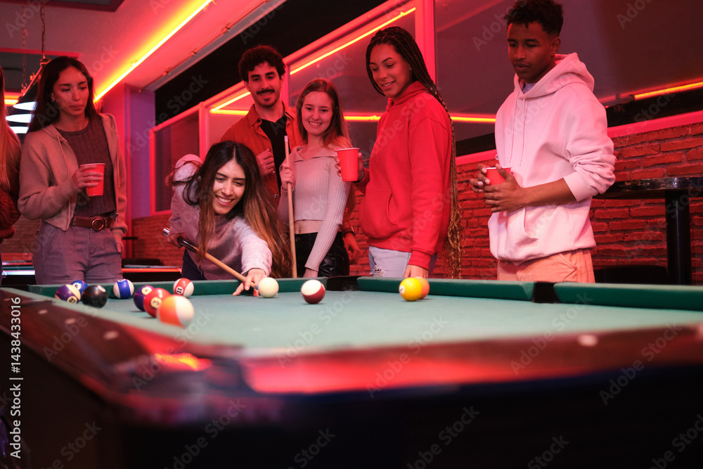 Group of friends enjoying a night out playing pool and having drinks in a trendy nightclub