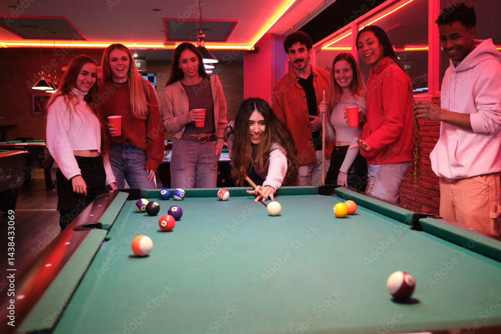 Group of friends enjoying a night out playing pool and having drinks in a trendy nightclub