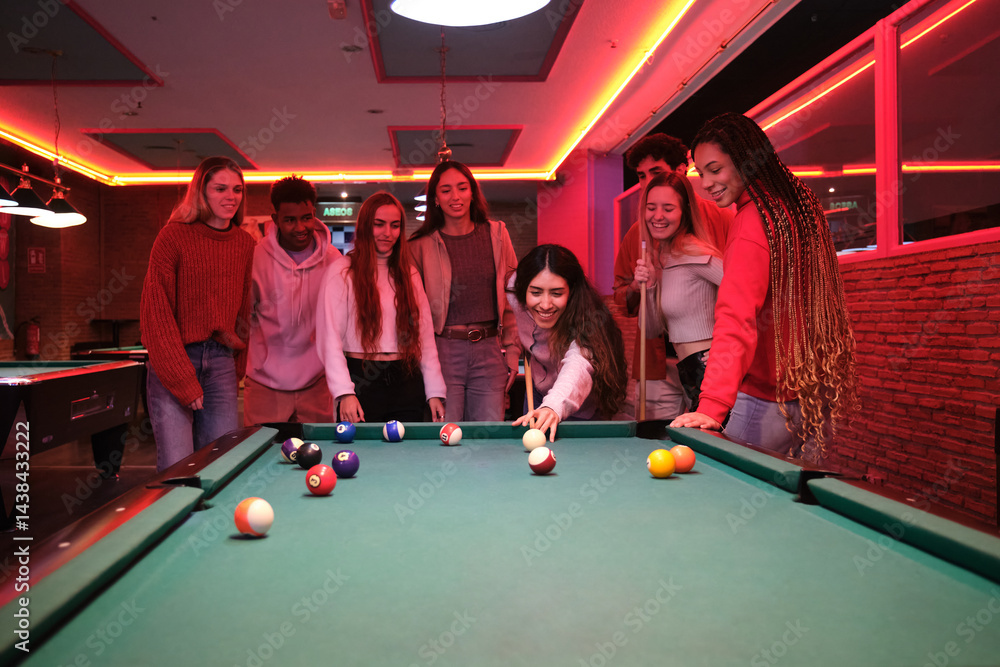 Young people having fun playing pool in a billiard hall with neon lights