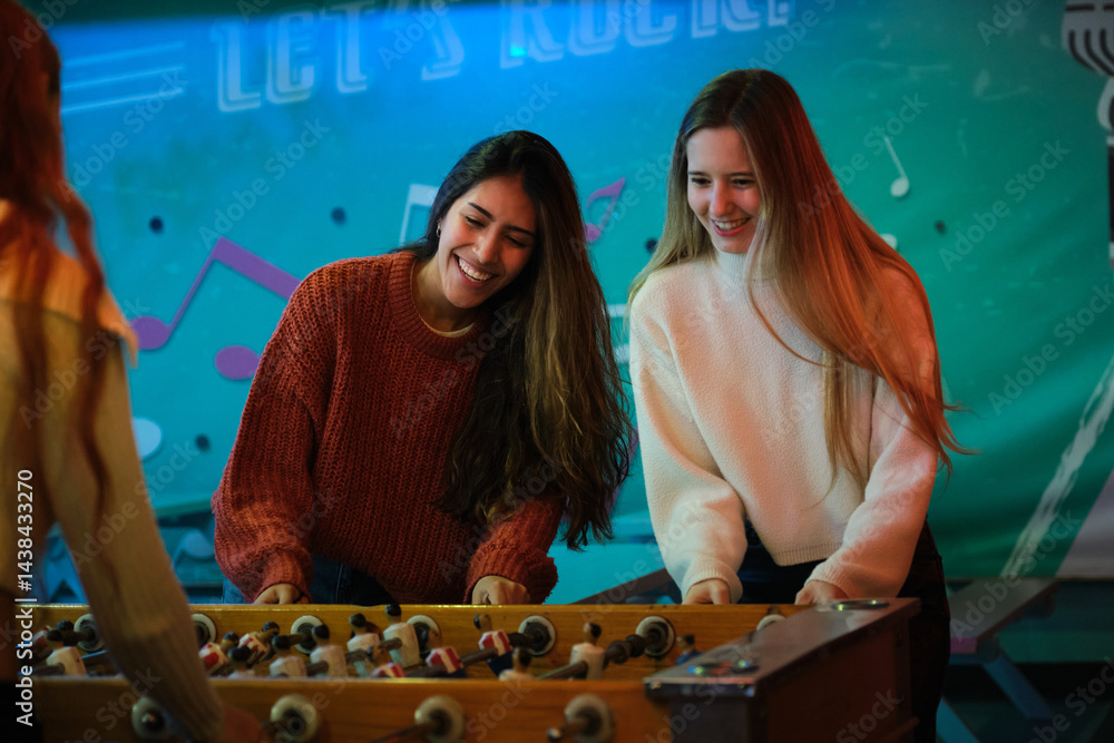 Two friends playing and having fun with a foosball table