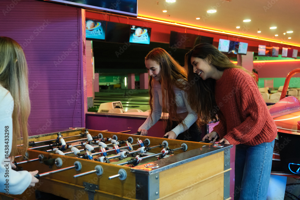 Group of friends having fun playing table soccer in an amusement arcade