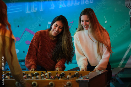 Two friends playing and having fun with a foosball table