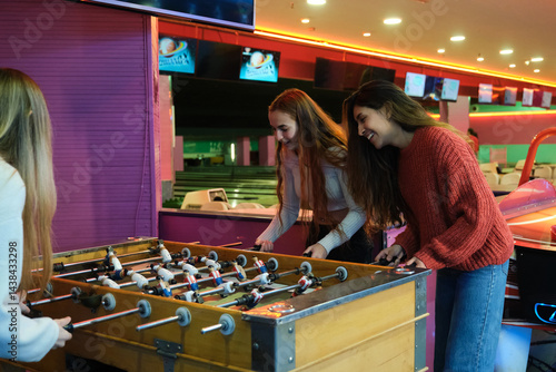 Obraz na płótnie Group of friends having fun playing table soccer in an amusement arcade w salonie