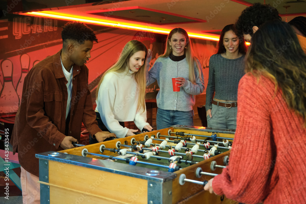 Group of young people enjoying a game of table football in a vintage bowling club