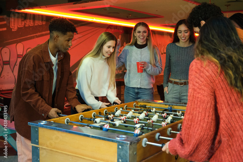 Obraz na płótnie Group of young people enjoying a game of table football in a vintage bowling club w salonie