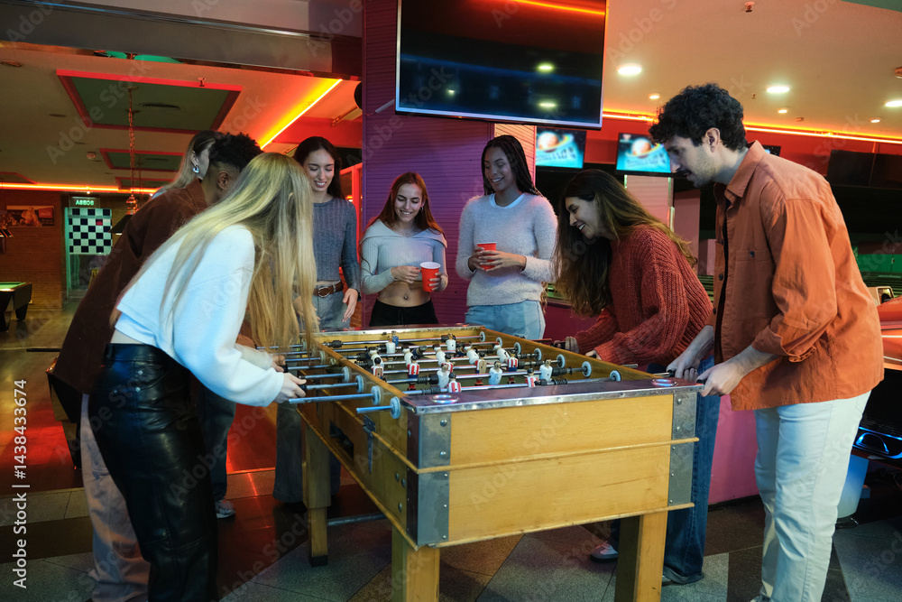 Group of friends enjoying a foosball game in a colorful arcade