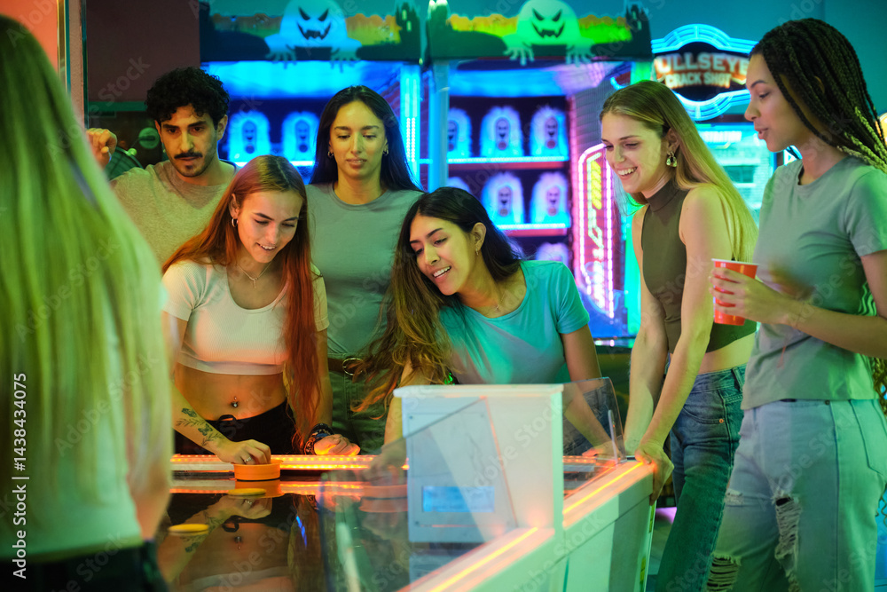 Young people having fun together playing air hockey in a colorful amusement arcade