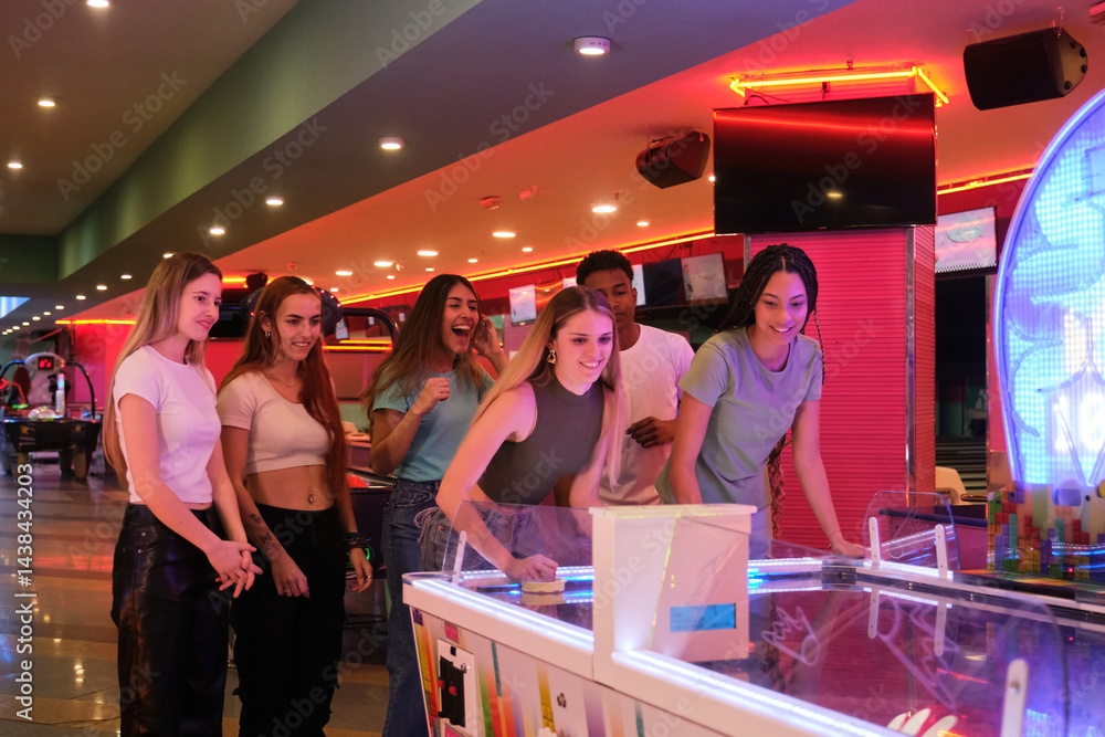 Group of young people enjoying a game of air hockey in vibrant arcade