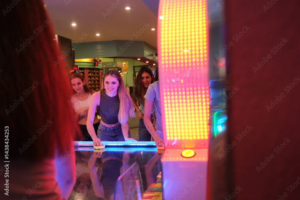 Group of friends enjoying a game of air hockey in a colorful arcade