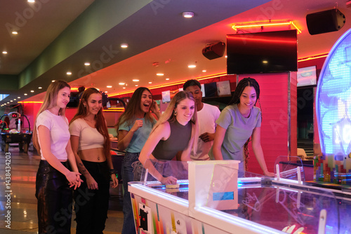 Obraz na płótnie Group of young people enjoying a game of air hockey in vibrant arcade w salonie