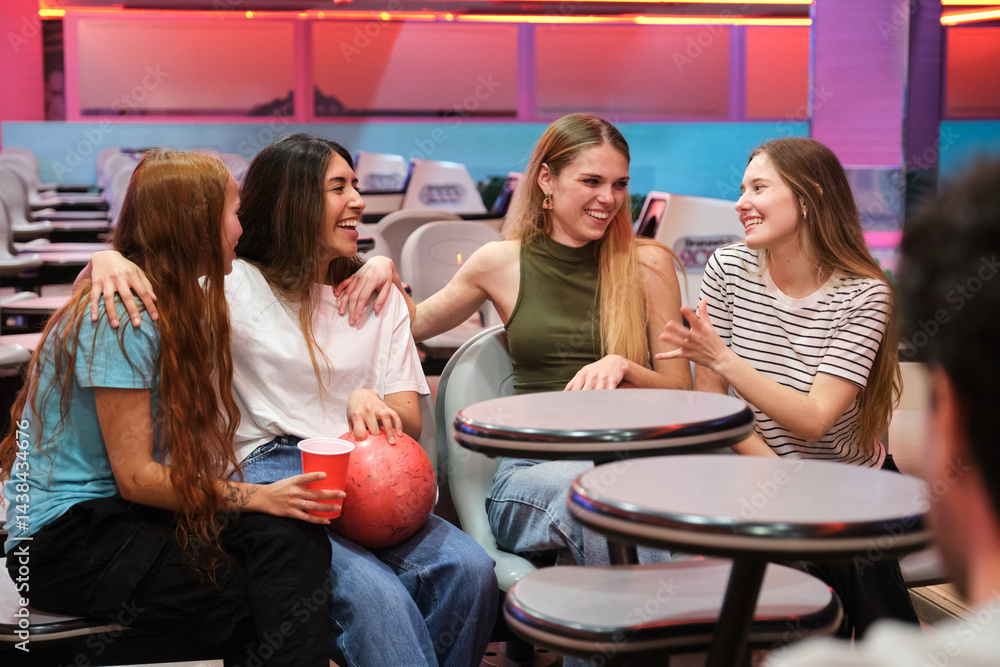 Four friends chatting and having fun together at bowling alley