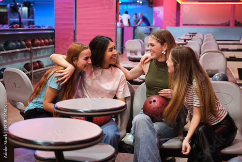 Four friends are sitting, chatting and having fun at the bowling alley