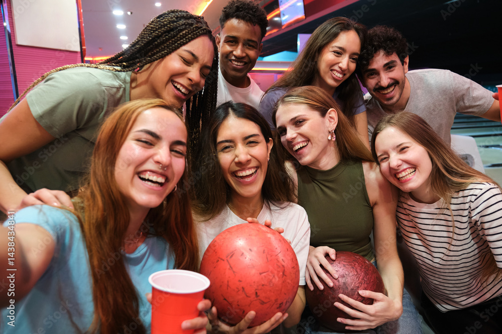 Happy friends taking selfie at bowling alley, holding bowling balls and drinks, enjoying their time together