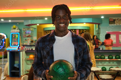 Obraz na płótnie Young bowler holding green bowling ball smiling in bowling alley w salonie