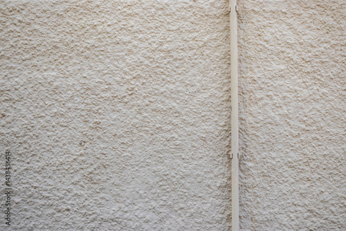 Textured wall with rough plaster finish and vertical plastic pipe. Neutral color, minimalist background