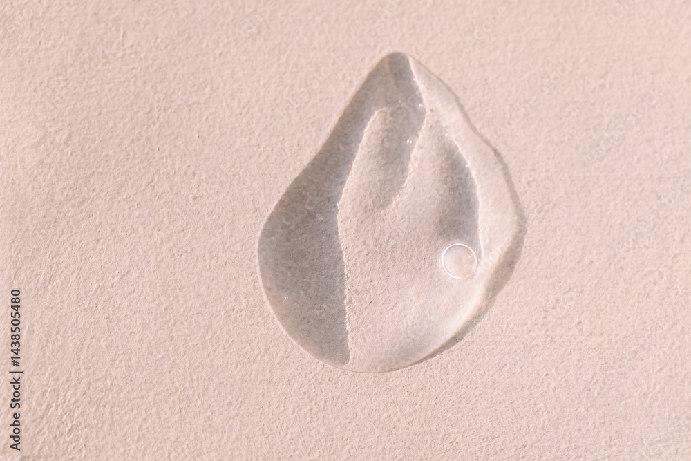 Obraz premium Close-up of a transparent gel smear with bubbles. Cosmetic products. A drop of serum or essence on a textured background. Bright sunlight.