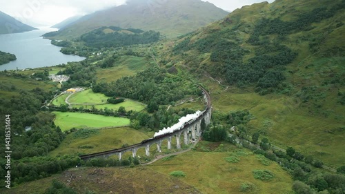 aerial view of a steam train over a viaduct with a valley and mountains in the background