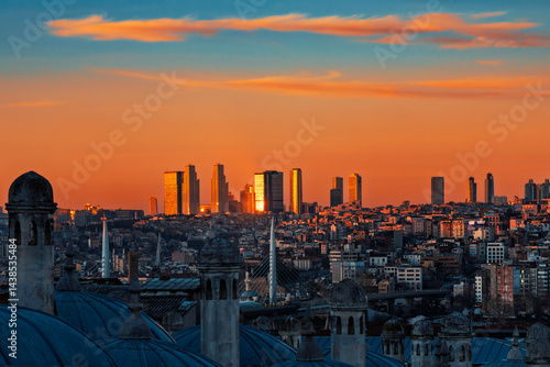 Istanbul skyline at sunset with modern skyscrapers glowing in golden light, seen from the rooftops of a historic district. Photo taken on March 6, 2025.