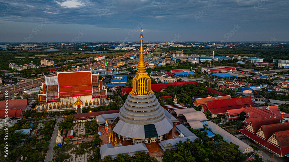 Naklejka premium Aerial view of The moon is situated on top of the golden umbrella of the golden pagoda Wat Ketmadi Sriwararam.. a magnificent golden pagoda surrounded by temple buildings...
