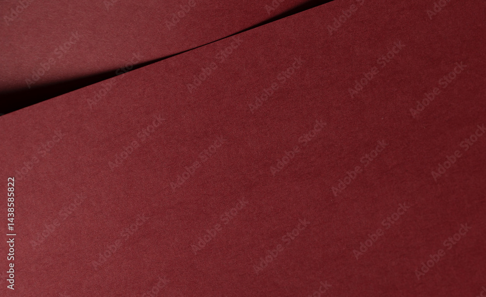 Fototapeta premium Matt paper texture with deep red and maroon tones, sleek folded design and bold contrast along curved edges. The smooth, modern composition offers an elegant, minimalistic backdrop with a premium,.