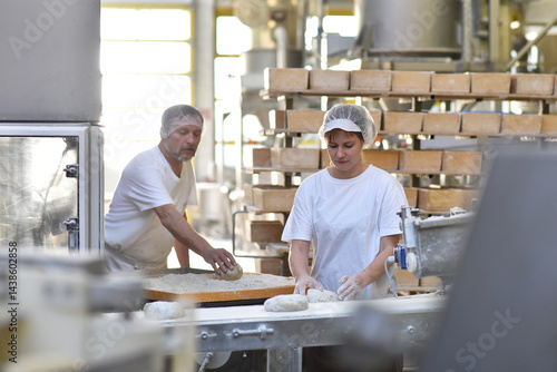 Worker in a large bakery - industrial production of bakery products on an assembly line