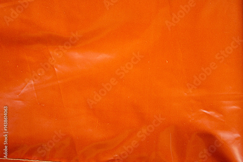 Crumpled orange plastic bag closeup texture background