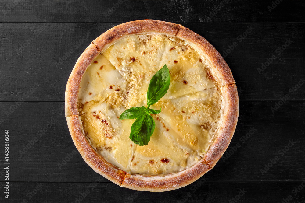 Delicious four cheese pizza with basil on black wooden table
