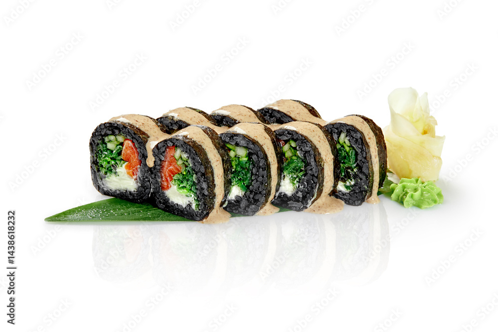 Black sushi rolls with salmon, vegetables and cream cheese drizzled with sauce on a green leaf