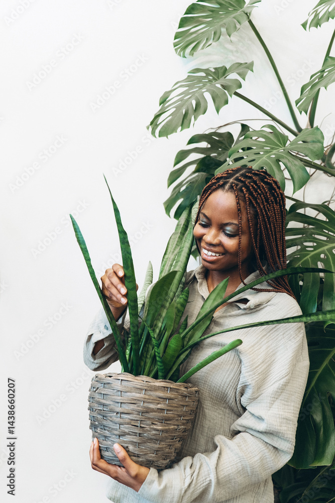 A woman lovingly nurturing her indoor plant in a beautifully arranged natural greenery setting
