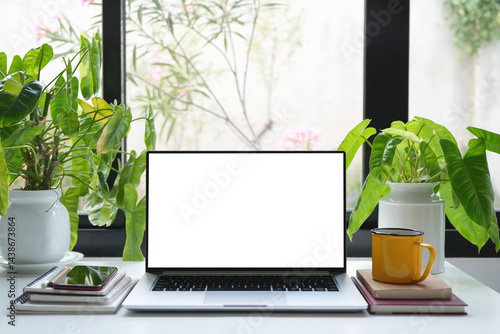 Laptop and phone with coffee and plant, cozy indoor workspace