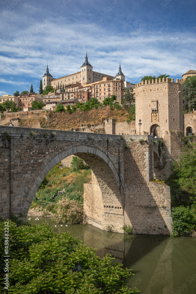 Vertical View of Stone Bridge and Alcázar of Toledo during Sunny Day in Spain. European Monument with Tagus River. Vertical View of Stone Bridge and Alcázar of Toledo during Sunny Day in Spain. European Monument with Tagus River.