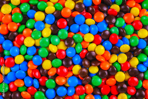 Obraz na płótnie Colorful candy-coated chocolates in a vibrant, playful pile. Bright red, blue, yellow, green, and orange sweets create a cheerful, festive background perfect for parties, designs, and advertisements. w salonie