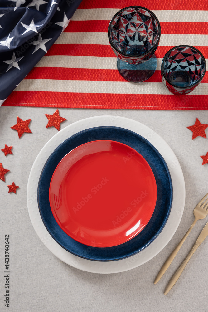 Table setting for USA Independence Day. Festive dinner with empty plate and decoration in USA national flag colors. Copy space. Vertical. View from above