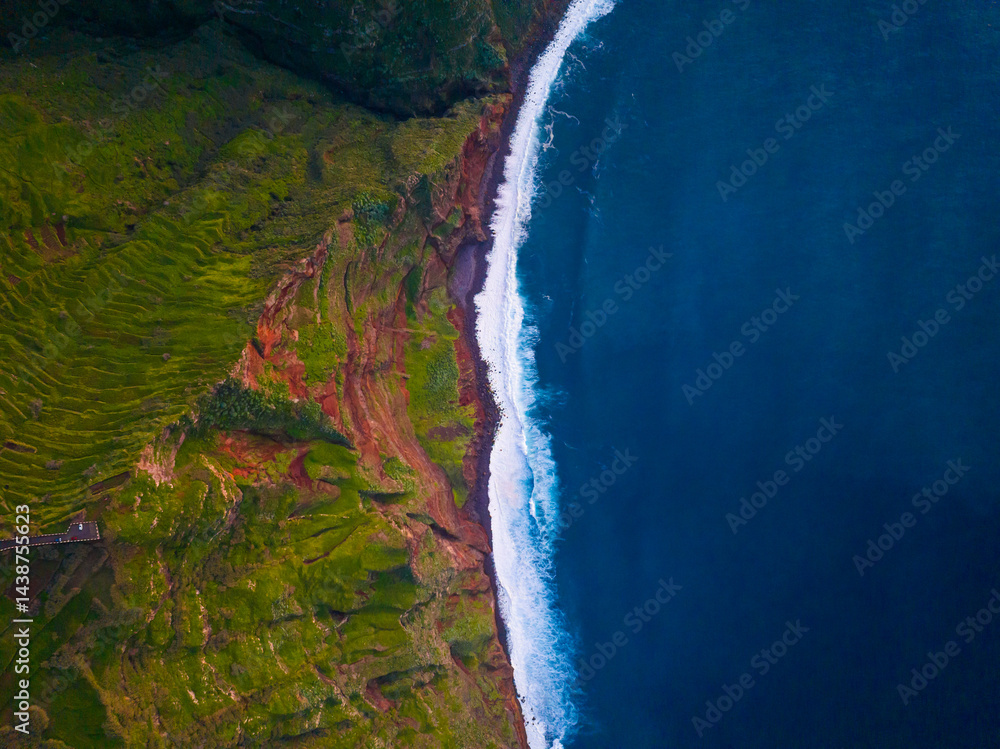 Breathtaking aerial view of the lush coastline meeting the deep ocean at sunrise