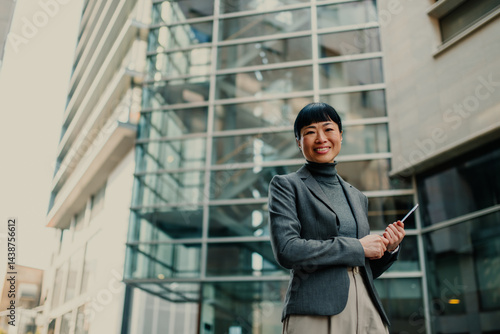 Wallpaper Mural Smiling businesswoman holding tablet in front of office building Torontodigital.ca